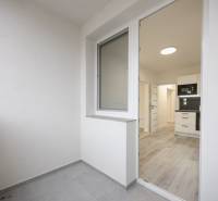 A balcony with a view of the kitchen area and a floor with a wooden decor in a 3-room apartment.