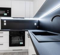 A kitchen in a 3-room apartment with black and white cabinets and a sink.