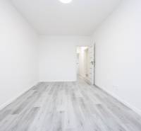 A room with white walls and a wooden decor floor in a 3-room apartment.