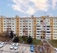 A panel apartment building on Jána Stanislava in Bratislava - Karlova Ves, with cars parked in front of it.