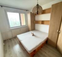 Bedroom with a bed and a wardrobe in a 2-room apartment with a wooden decor floor.