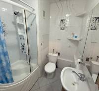 Bathroom with a bathtub, sink, and toilet in a 2-room apartment, white tiles, blue shower curtain.