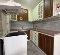 A kitchen in a 2-room apartment with dark brown and white cabinets and a stainless steel countertop.