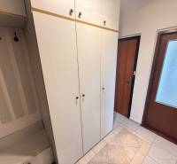 Entrance hall in a 2-room apartment with wardrobes and hangers, floor with wooden decor.