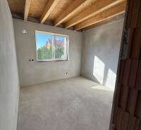 Interior of a family house with a view of the walls, window, and wooden ceiling.