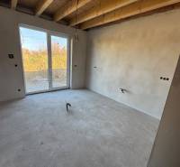 Under-construction interior of a family house with ceiling beams and a large window to the garden.