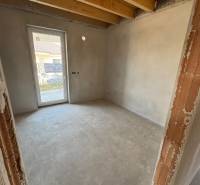 Interior in a family house with unfinished walls and wooden ceiling beams.