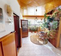 Interior of a family house with plants, chairs, a calendar, and wooden wall decorations.