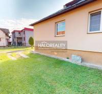 The garden of a family house in Krasňany with a lawn, next to it are other houses.