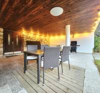 Covered terrace with a stone wall, rattan furniture, and lighting, ideal for relaxation.