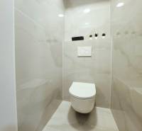 Bathroom with toilet in a 2-room apartment, tiled with light ceramic tiles.