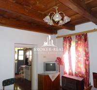 Living room in a family house with a wooden ceiling, curtains, and a television.