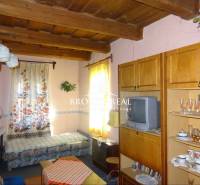 Living room in a family house with a wooden beam ceiling, furniture, and a television.