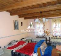 A room in a family house with a wooden ceiling, sofas, and colorful curtains.