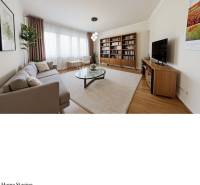 Living room with a sofa, television, bookshelf, and wooden decor flooring in a family house.