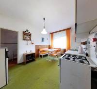 A kitchen in a family house with a gas stove, retro furniture, and a green carpet.