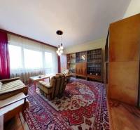 Living room in a family house with carpets, comfortable seating, and a glass cabinet.