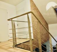 A staircase with a metal railing and a wooden decor floor in a family house.