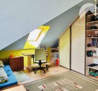 Attic room with a window, bed, and shelves, floor with wooden decor.
