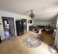 Living room in a family house with carpets, a sofa set, and a display cabinet.