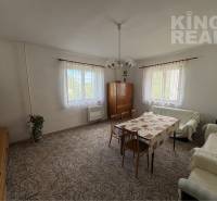 Living room in a family house with carpet flooring, wooden furniture, and large windows.
