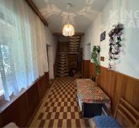 A hallway in a family house with floral decorations, a window curtain, and wooden paneling.