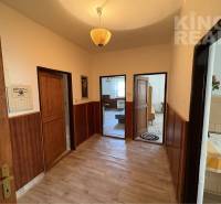 A hallway of a family house with a wooden-patterned floor and multiple doors.