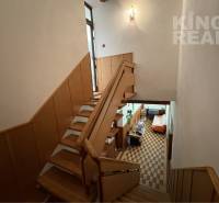 A staircase in a family house with wooden railings leading to the living room.