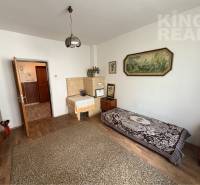 A room in a family house with a wooden decor floor, a bed, and a picture on the wall.
