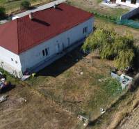 A family house in Zemianska Olča with a red roof, lawn, and boat trailers in the yard.