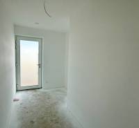 A hallway in a family house with white walls, concrete floor, glass doors.