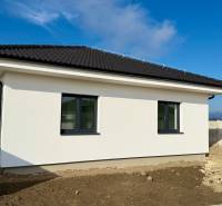 A family house in Topoľnica with a pitched roof and white facade on an empty plot.