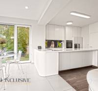 A kitchen in a family house with white cabinets, a wood-patterned floor, and a dining table.
