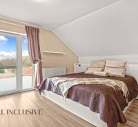 Bedroom in a family house with a balcony, bed, and wooden decor flooring.