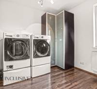 Laundry room in a family house with a washing machine, dryer, and wooden decor flooring.