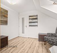 Attic room in a family house with a wooden-patterned floor and a patterned armchair.