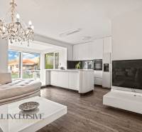 Living room and kitchen with a chandelier, sofa, white furniture, and wood-patterned flooring.