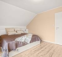 A bedroom in a family house with a wooden decor floor and simple furniture.