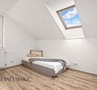 Attic room in a family house with a bed and a skylight, floor with wooden decor.