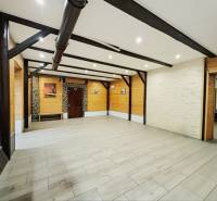 An open room in a family house with wooden decor on the walls and ceiling beams.