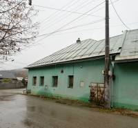 A family house in Kolárovice with a green facade, a metal roof, during rainy weather.