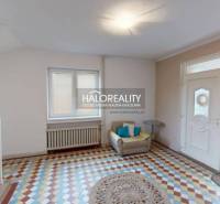 The entrance hall of a family house with colorful tiles, a chair, and a window.