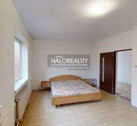 A bedroom in a family house with a double bed and a wooden-patterned floor.