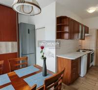 A kitchen in a 3-room apartment with a wooden decor floor and a kitchen unit.