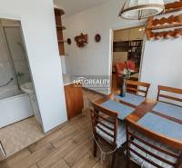 Dining area and part of the bathroom in a 3-room apartment with wood-patterned flooring.