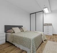Bright bedroom with a bed, wardrobe, and wooden decor flooring in a 3-room apartment.
