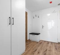 Entrance area with white cabinet furniture, a bench, and a wooden decor floor in a 3-room apartment.