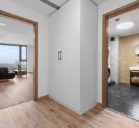 Interior of a 3-room apartment with a wooden decor floor, white cabinets, and a bathroom.