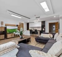 Living area in a 3-room apartment with a kitchen, wooden decor flooring, and a comfortable sofa.