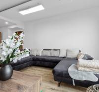 Living room with a dark sofa, white cushions, and a wooden decor floor.
